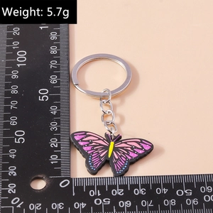 Detail eines rosa-violetten Schmetterling-Schlüsselanhängers mit Lineal zur Größenmessung