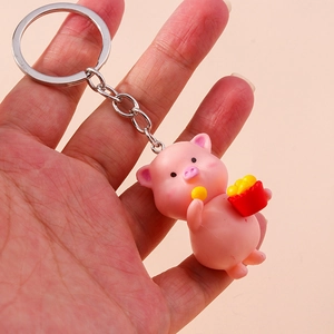 Detail showing a cute pink pig keychain figurine holding a red french fry box accessory