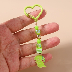 Détail d'un porte-clés dinosaure vert avec dragonne perlée et mousqueton en cœur