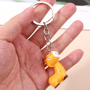 Detail of a yellow cartoon giraffe keychain charm with silver metal ring held by a hand
