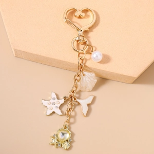 Detailed close-up of golden keychain with starfish, pearl, and shell charms on display