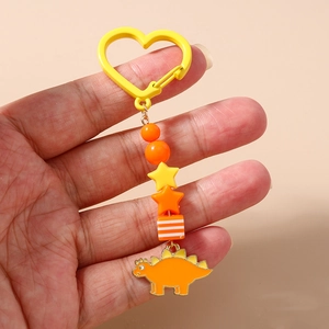 Détail d'un porte-clés dinosaure orange avec perles et mousqueton en forme de cœur