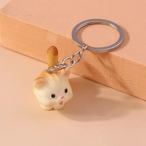 Close-up of cute cartoon orange cat keychain accessory on a matching minimalist pedestal