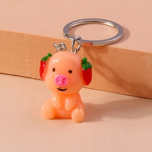 Close-up of pink pig keychain with red strawberry hat and silver ring attachment