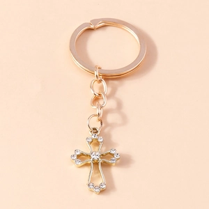 Detailed view of a gold cross keychain featuring hollow patterns and crystal rhinestones