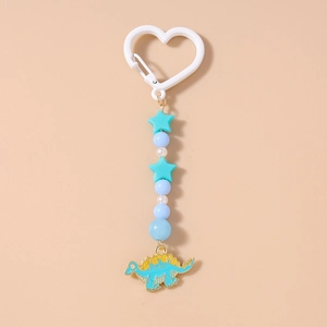Détail du porte-clés perlé avec étoiles bleues et pendentif dinosaure en émail