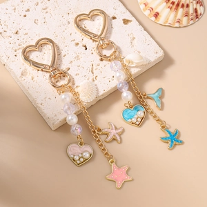 Porte-clés océan doré avec coquillage étoile de mer et perles sur une surface en pierre