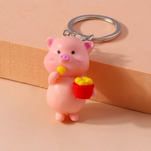 Detail of pink cartoon pig keychain holding a red bucket with metallic silver key ring
