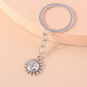 Detailed close-up of retro silver sun and moon keychain on a minimalist stand