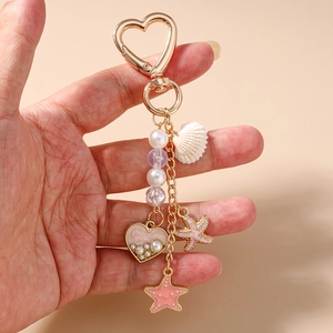 Détail d'un porte-clés cœur doré avec des pendentifs étoile de mer et perles