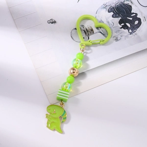 Détail d'un porte-clés dinosaure vert avec crochet en forme de cœur et perles colorées