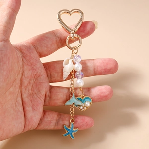 Détail d'un porte-clés doré avec étoile de mer bleue, coquillage et perle d'imitation