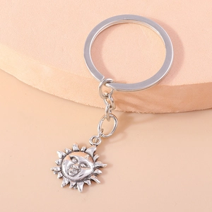 Vintage bohemian silver sun face keychain with moon and cloud elements on display