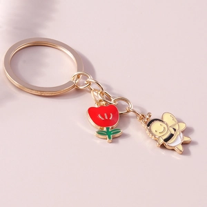 Detailansicht eines goldenen Schlüsselanhängers mit Tulpe und kleiner Biene