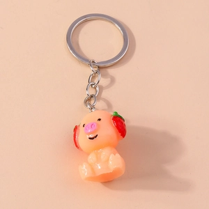 Detailed view of a cute resin pig keychain with red strawberry earmuffs and silver ring