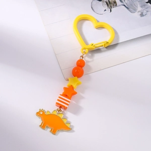 Détail d'un porte-clés dinosaure avec anneau cœur orange et stégosaure coloré en émail