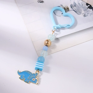 Détail d'un porte-clés dinosaure bleu avec chaîne en perles et fermoir en forme de cœur