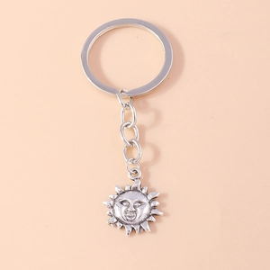 Macro shot of vintage silver sun keychain with smiling face and radial sunburst texture