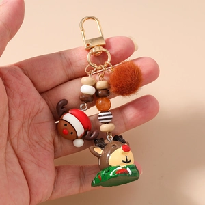 Detail of Christmas reindeer keychain featuring plush ball and festive beads on gold hook