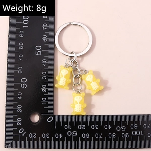 Macro detail of three yellow skeleton bears keychain with silver metal ring and chain