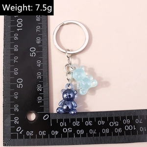 Macro shot of blue resin bear keychains on a ruler showing 7.5g weight and size details