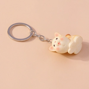 Close-up of cute cartoon cat keychain with orange spots on a soft pink background