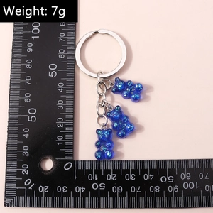 Blue resin glitter bear keychain with measurements and 7g weight displayed on scale