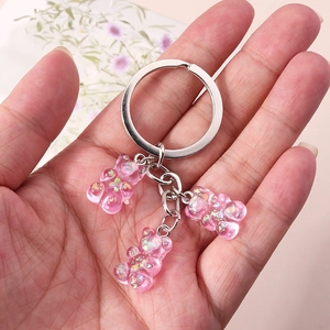 Detailed shot of pink resin gummy bear keychains with glitter held in a hand