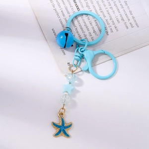 Détail d'un porte-clés perlé avec breloque étoile de mer bleue, cloches et perles craquelées