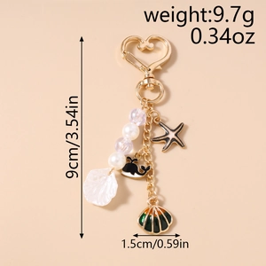 Detail of ocean-themed keychain with gold heart clasp, pearls, whale and starfish charms