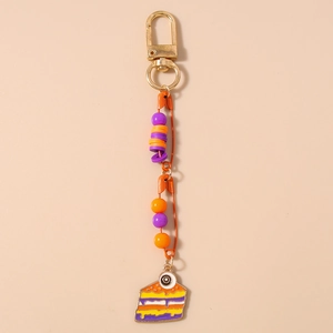 Detail of handmade orange safety pin keychain with purple beads and cake slice charm