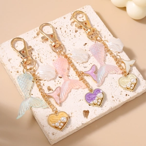 Mermaid tail keychains with shells and pearl hearts in green, pink, and purple colors
