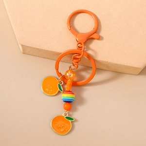 Vue détaillée des breloques orange avec feuilles émaillées et perles acryliques rayées