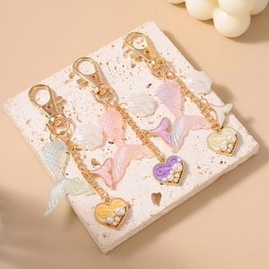 Detail of mermaid tail keychains with shells and pearl hearts on golden metal chains