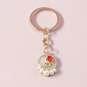 Detail of rose gold keychain featuring a red rose circle pendant with crystals and pearls