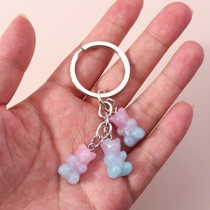 Detail of hand held silver keychain with three pink and blue gradient glitter resin bears