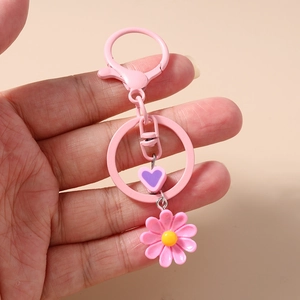 Dettaglio del portachiavi a margherita rosa con ciondolo a cuore viola e moschettone
