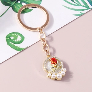 Golden rose keychain featuring a red flower with rhinestones and white pearls on floral card