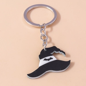 Detail of black Halloween witch hat keychain with white bat pattern on a pink background