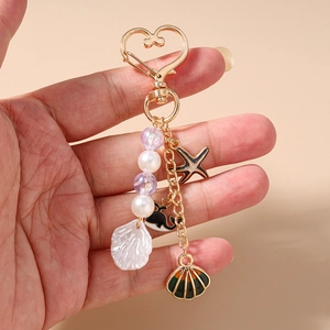 Handheld ocean-themed keychain with whale starfish and shells on golden heart clasp