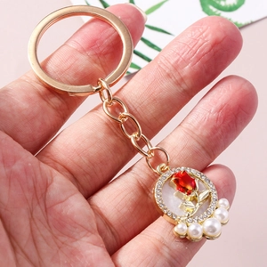 Golden keychain featuring a 3D red rose pendant with crystal rhinestones and white pearls