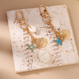 Marine style keychain with golden starfish, pearls and natural shells on stone base