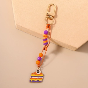 Detail of Halloween cake keychain with gold clasp, orange beads and enamel eye charm