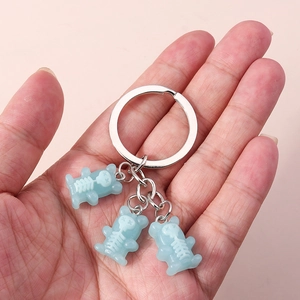 Detail showing three translucent light blue skeleton bear charms on a silver metal keyring