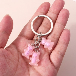 Detail of hand holding a silver keyring with three pink skeleton bear charms