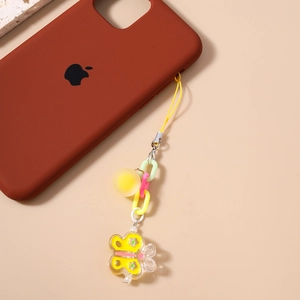 Detail of yellow acrylic butterfly and matte bead keychain on a brown phone case