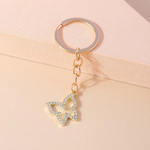 Porte-clés papillon doré à la mode avec design creux et strass blancs pour sacs