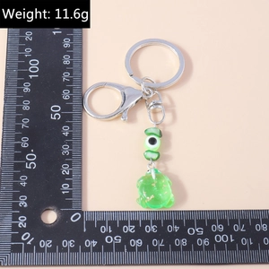 Detail view of cartoon frog keychain with evil eye bead and dimensions on scale