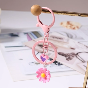 Primo piano del portachiavi a margherita rosa con cuore viola su supporto dorato