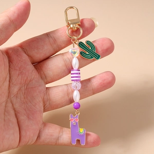 Handheld view of a colorful beaded keychain with purple alpaca and green cactus charms